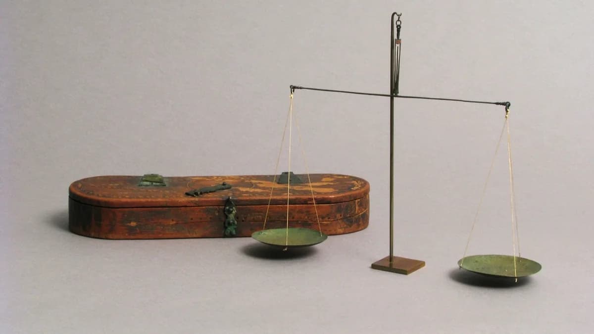 Antica bilancia a piatti in bronzo posizionata sopra una scatola di legno intagliato a mano