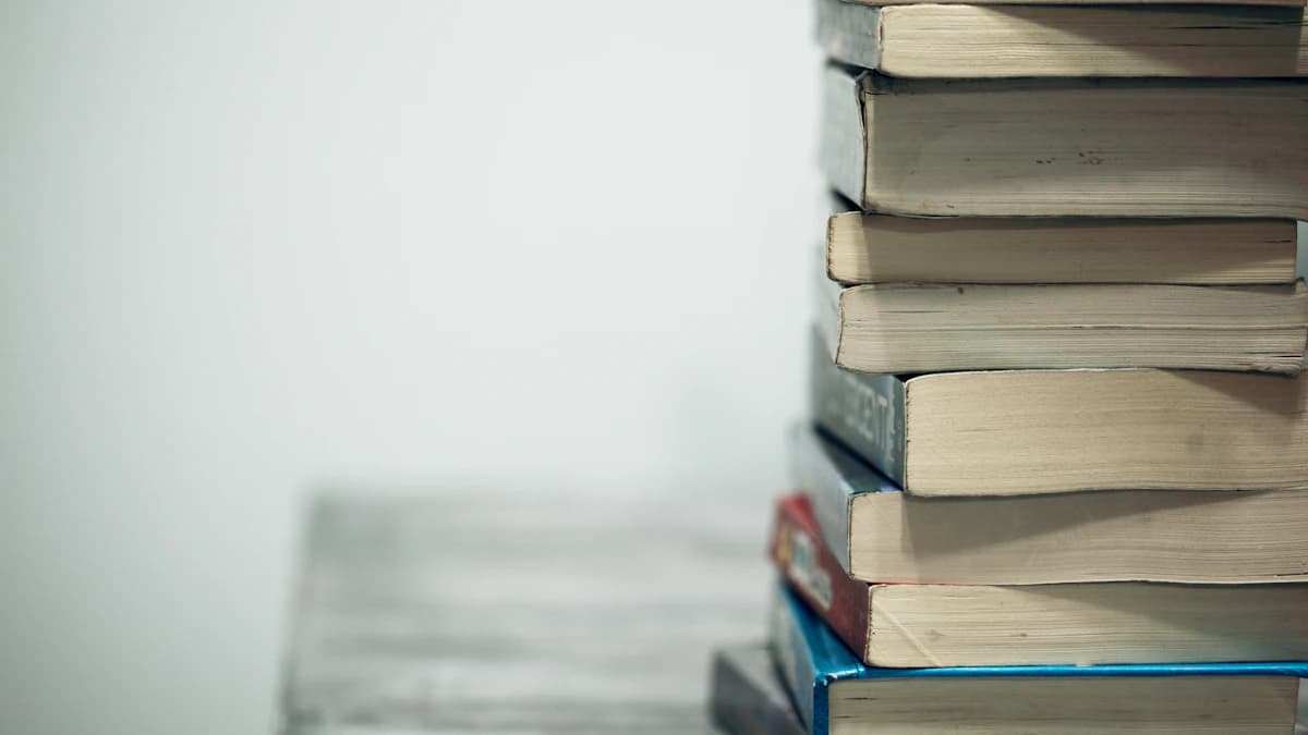 Una pila ordinata di vecchi libri e quaderni poggiati su un tavolo di legno minimalista