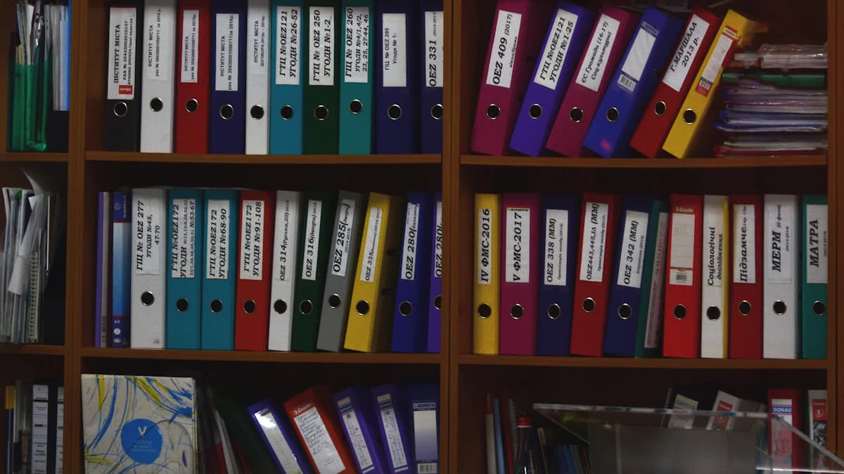File di raccoglitori ad anelli colorati allineati su scaffali di legno in un ufficio