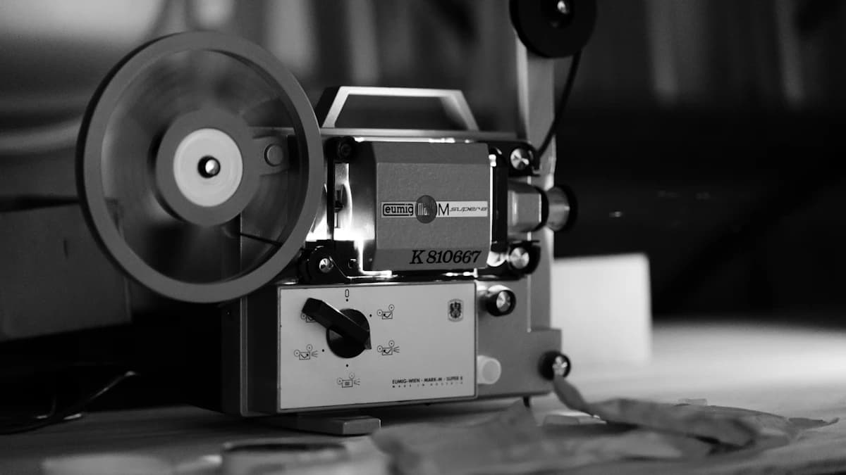 Un proiettore cinematografico d'epoca in bianco e nero appoggiato su un tavolo