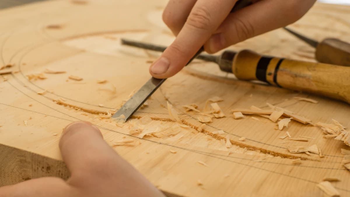 Mani artigiane che intagliano con cura un blocco di legno in laboratorio
